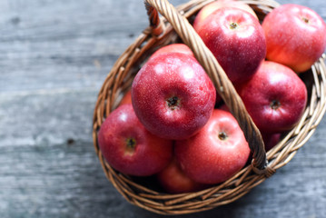 basket with red apples on wooden background