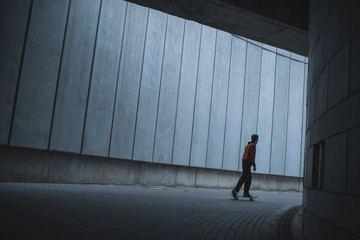 Fototapeta na wymiar skateboarder riding at urban location with grey concrete walls