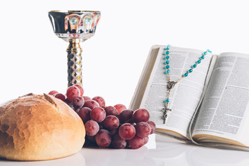 open holy bible, food, chalice and christian cross on white for Holy Communion