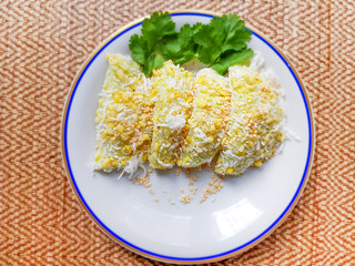 Thai traditional dessert, Thai sweet dessert, mung bean rice-crepe and coconut,white sesame in white plate on wooden table background.