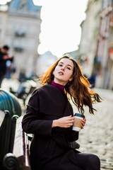 Fototapeta premium Elegant woman with long hair drinks coffee at the table