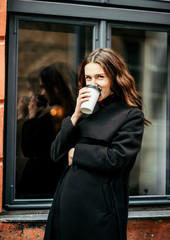 A sincere girl stands with coffee in her hands
