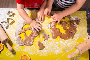 Cute little boy and girl twins preparing Christmas cookies in the kitchen