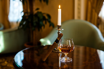 A glass of cognac and a cigar on the table.