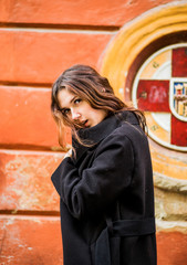 A charming girl in a black coat poses on the street