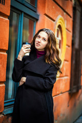 A sincere girl stands with coffee in her hands