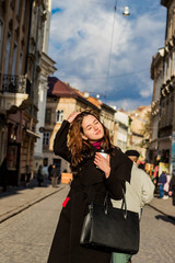 Fototapeta premium Brunette woman with long hair posing with coffee in the hands of the street