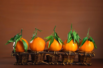 Seasonal and holidays concept. Group of tangerines in a vintage wicker basket on a brown background. New Year in tropic.