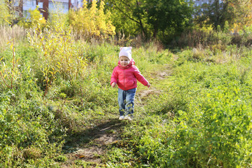 Naklejka na ściany i meble Lovely smiling 1 years girl walking in autumn outdoors