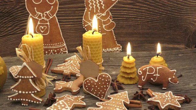 Christmas homemade gingerbread cookies on wooden desk. Yellow scented candles made from natural beeswax.