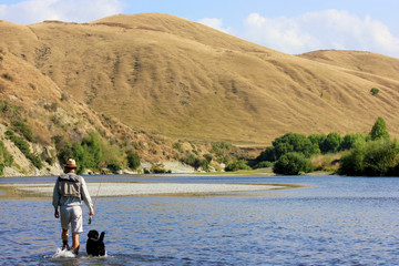 Fototapeta na wymiar Fishing with Black Labrador New Zealand River