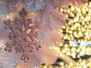The selective focus of snowflake on with the background of yellow christmas tree shape bokeh along the wires of christmas decoration. Merry Xmas everyone