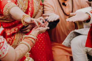 Indian newlyweds take something from mother's hands covered with henna tattoos