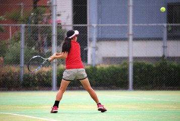 テニスでバックハンドを打つ女の子