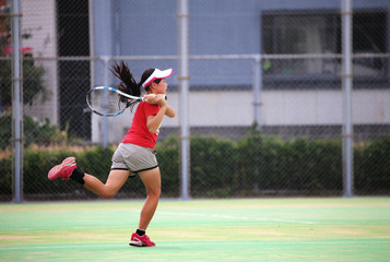 テニスでバックハンドを打つ女の子