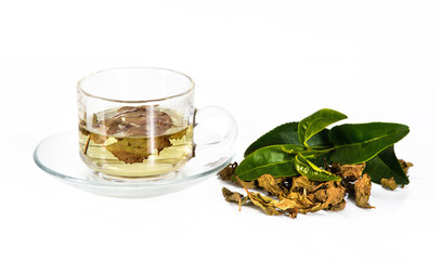 transparent glass cup with tea on the saucer with dry tea leaves on a white background