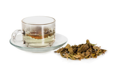 transparent glass cup with tea on the saucer with dry tea leaves on a white background