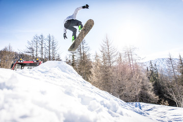 Naklejka na ściany i meble Snoboarder performing tricks on the snow