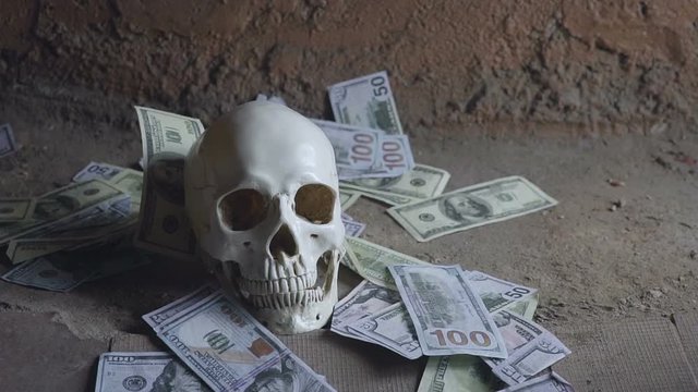 Money greed concept with human skull, skull and falling money.