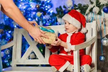 boy in santa costume receives christmas gift