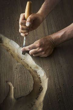 A craftsman using a chisel to carve out a deep groove in a piece of wood. 