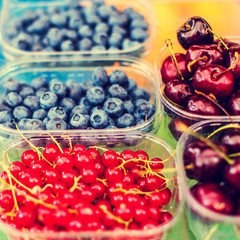 Berry fruits at marketplace  - organic  blueberries, raspberries, strawberries, cherries. Healthy local food market concept  in vintage hipster style..