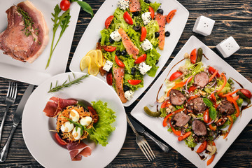 Food. Salads from vegetables, salmon, veal, steak, meat. On a wooden background. Top view. Free...