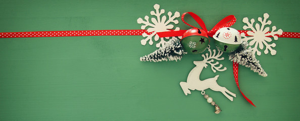 Christmas background with red silk traditional ribbon, white deer, evergreen tree, paper snowflakes and jingle bells.