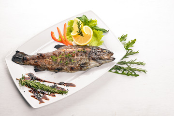 Fish Trout baked with vegetables and spices. On a wooden background. Top view. Free space for text.