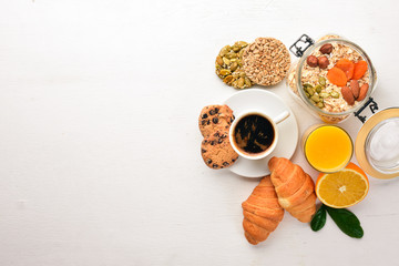 A healthy breakfast. Orange juice, kiwi, croissants, cookies, coffee, on a wooden surface. Top view. Free space for text.