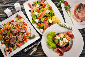 Food. Salads from vegetables, salmon, veal, steak, meat. On a wooden background. Top view. Free space for text.