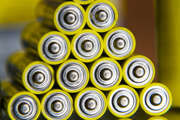 Stack of yellow AA batteries close up abstract coloured background