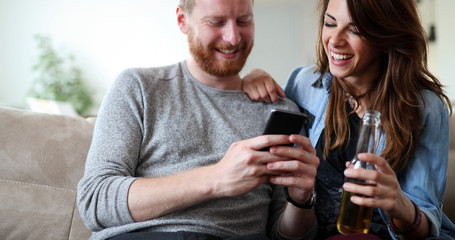 Relaxed couple or friends using mobile phone together to shop online