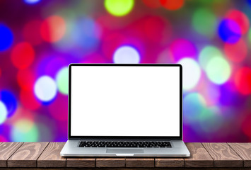 Modern laptop with empty white screen on wooden table against blurred Christmas lights background