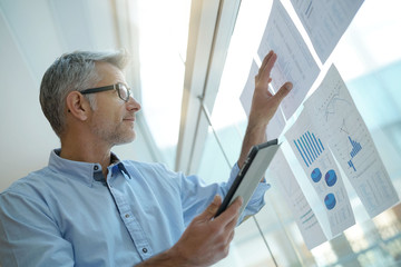 Businessman analyzing results charts hanged on office window