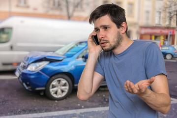 Sad man is calling to assistance after car accident.