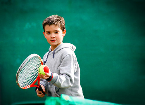 Little tennis player on a blurred green background.