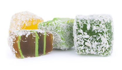 Yellow, green and brown Turkish Delight in coconut chips isolated on white background