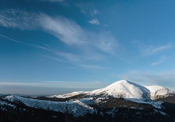 Winter landscape with mountain range at the background. Deep blue sky over the mountain range in winter