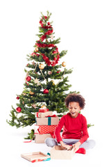 Obraz na płótnie Canvas Portrait of cute mixed race little boy unpacking gifts near Christmas tree and taking digital tablet out of box