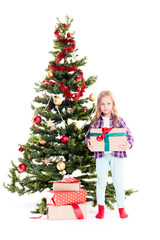 Portrait of little girl standing near Christmas tree with gift box in her hands on white background