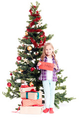 Portrait of little girl standing near Christmas tree with letter to Santa in her hands on white background