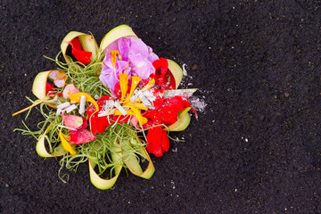Closeup image of balinese offering on the black sand background, Indonesia