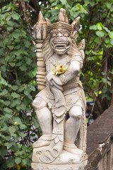 Fototapeta na wymiar Balinese traditional statue and offering to gods in the beggining of bridge in Bali, Indonesia