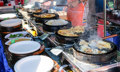 Many fried mussel pancakes with egg on the pan with smoke and preparing plate for food