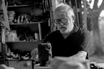 Senior sculptor working on his clay sculpture in his workshop. Black and white.