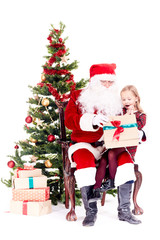 Fototapeta na wymiar Cute little girl receiving gift from Santa Claus sitting on his lap near Christmas tree