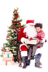 Fototapeta na wymiar Mixed-race little boy receiving Christmas gift from Santa Claus while sitting on his lap