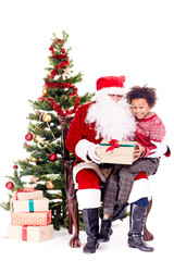 Mixed-race little boy receiving Christmas gift from Santa Claus while sitting on his lap