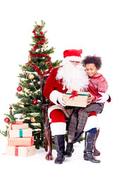 Mixed-race little boy receiving Christmas gift from Santa Claus while sitting on his lap